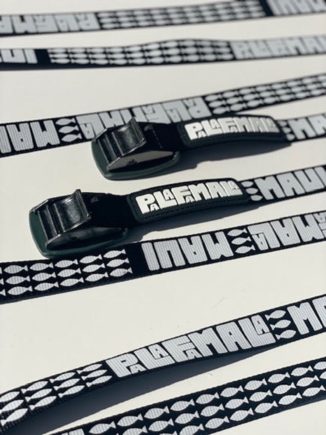 Black straps Palafamala branding on a white background