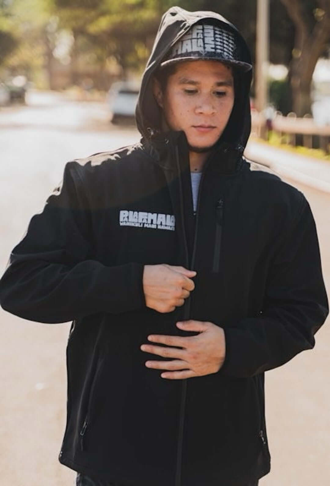 Person wearing a black hoodie with a brand logo outdoors