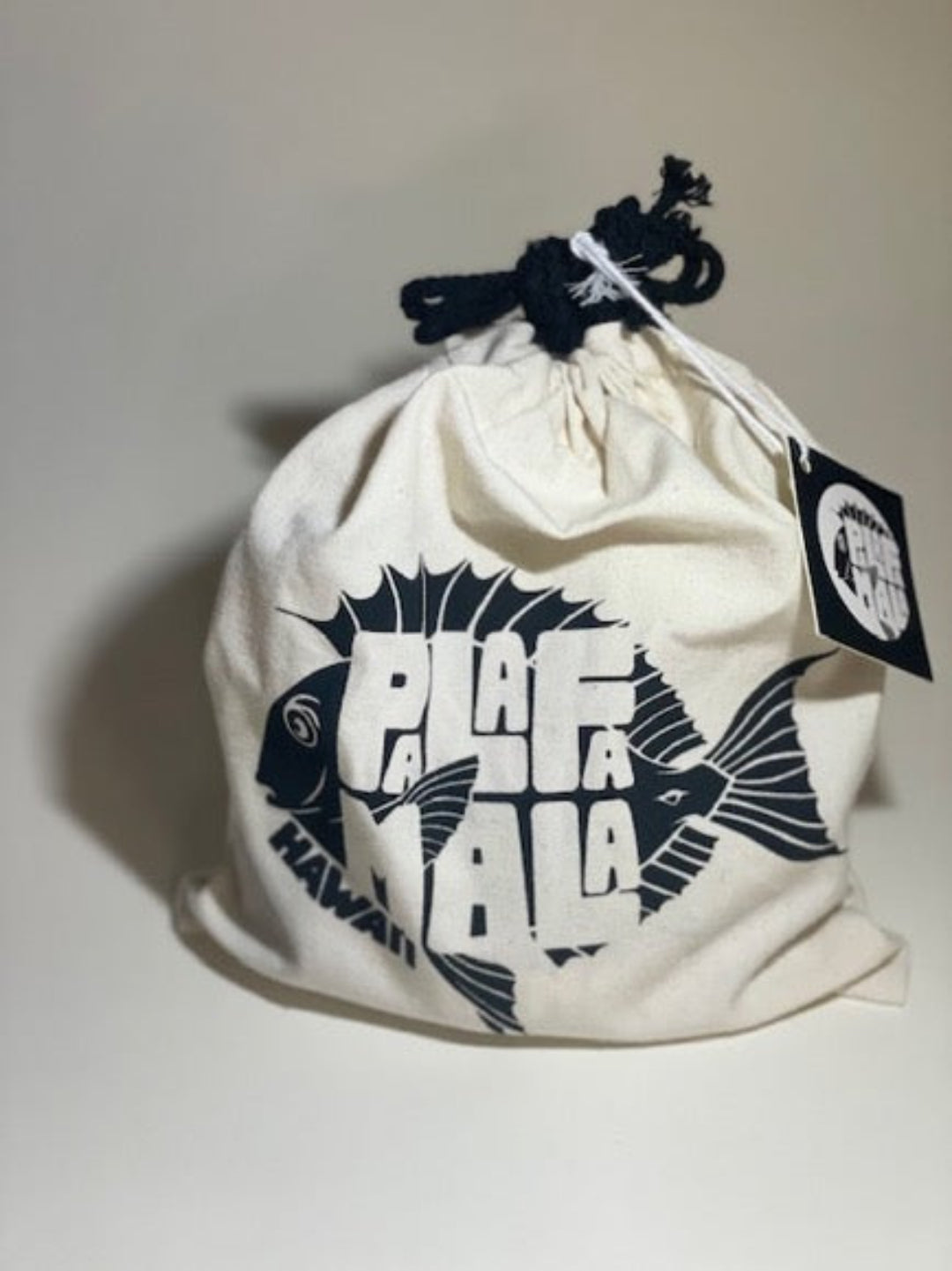 White drawstring bag with black fish design and 'PALAFAMALA' text on a light gray background